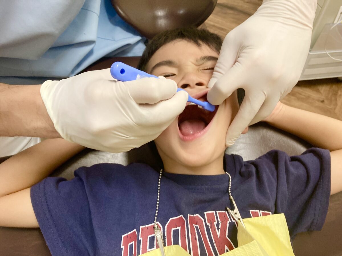 歯医者で歯磨きを指導される子ども